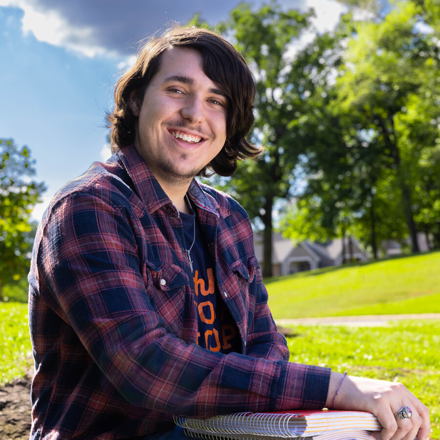 A male first-year student sits outdoors on The University of Texas at Tyler's campus