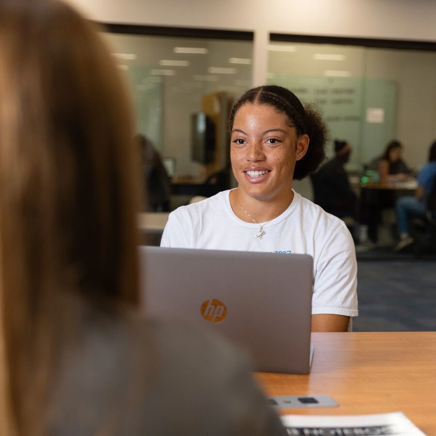 UT Tyler students working at a table with books and laptop computers