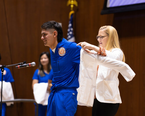 Male nursing student getting his white coat at a ceremony
