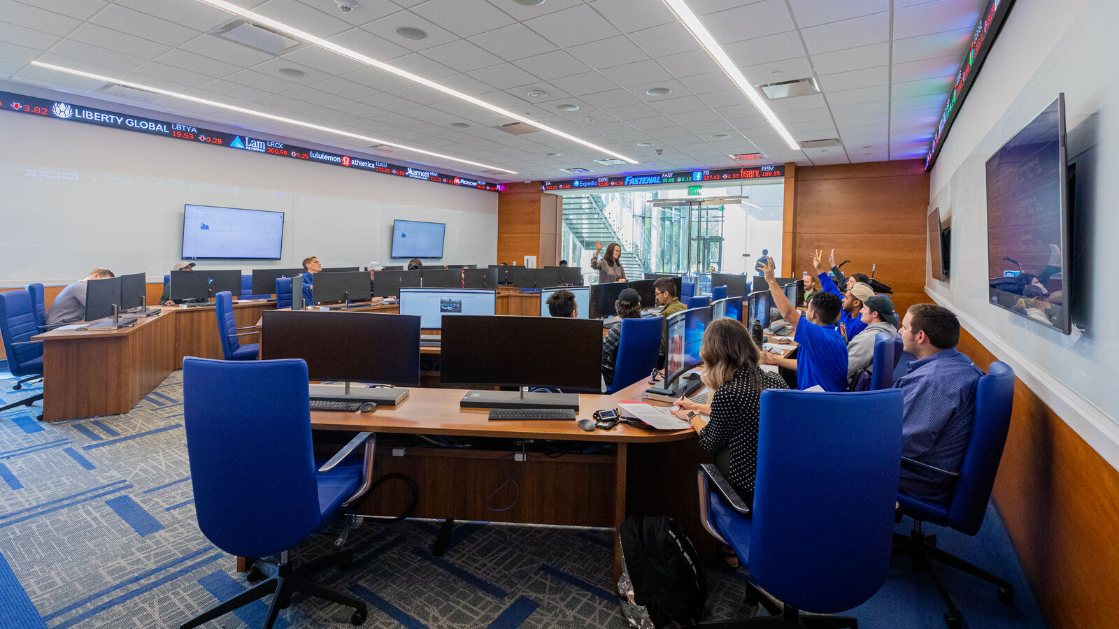 Economics students raise their hands during class on the Soules College of Business mock trading floor at The University of Texas at Tyler