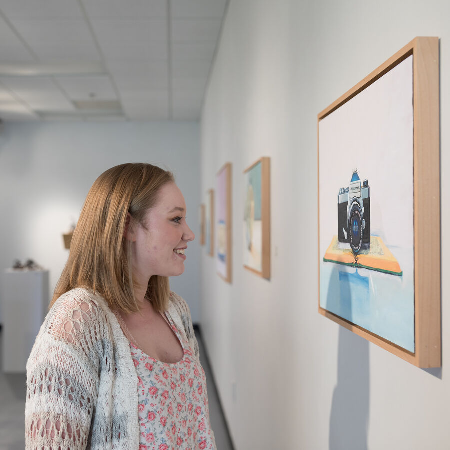 A female student observes a painting in one of UT Tyler's art galleries