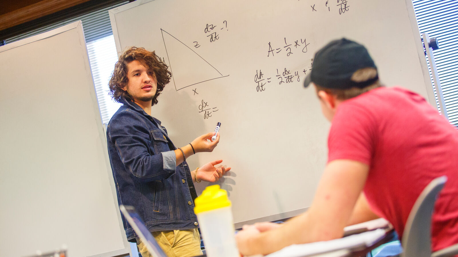 Two male mathematics majors at UT Tyler work on a problem on a white board