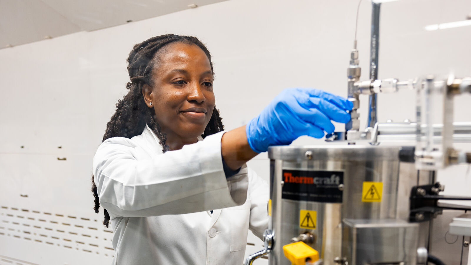 A female MS in Chemistry student checks on a chemical reactor in the chemical engineering lab at UT Tyler