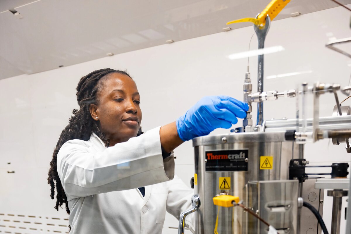A chemical engineering student, interacting with a chemical reactor