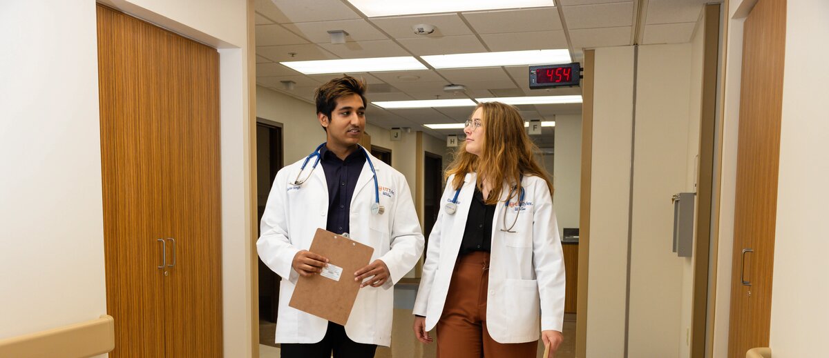 Two medicine students walking down a hospital hall