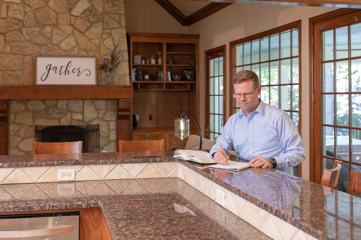 Man in glasses working on class work at a countertop