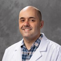 bald man in a white coat posing for a photo