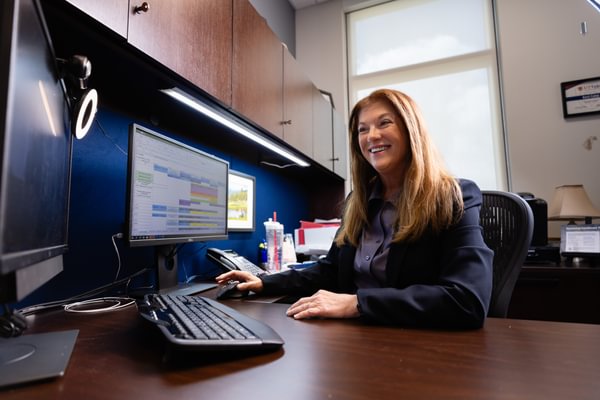 Faculty smiling and viewing information on a computer screen