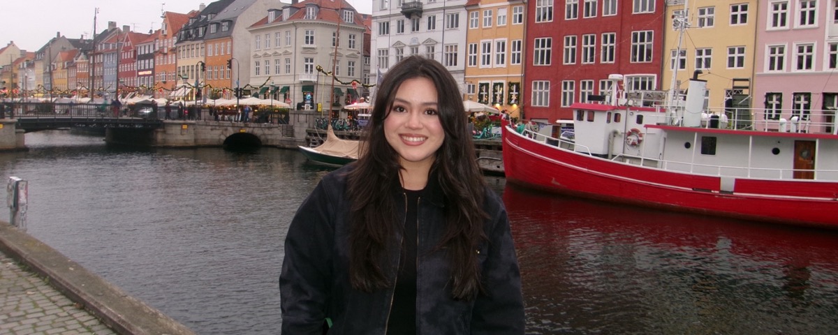 Student in front of colorful buildings in Copenhagen. 